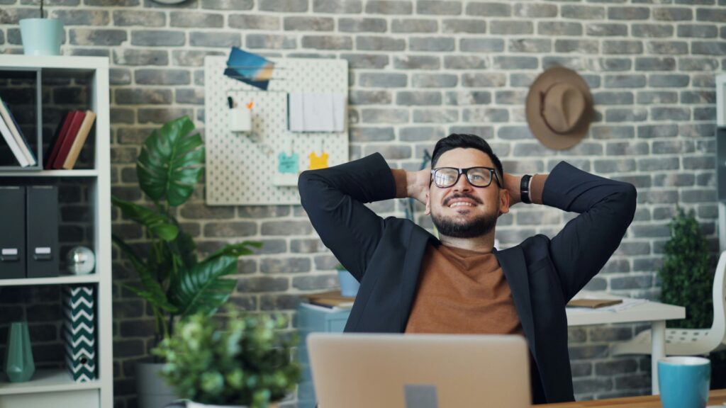 Professional in a relaxed posture at his desk, symbolizing reduced stress and burnout from mindfulness
